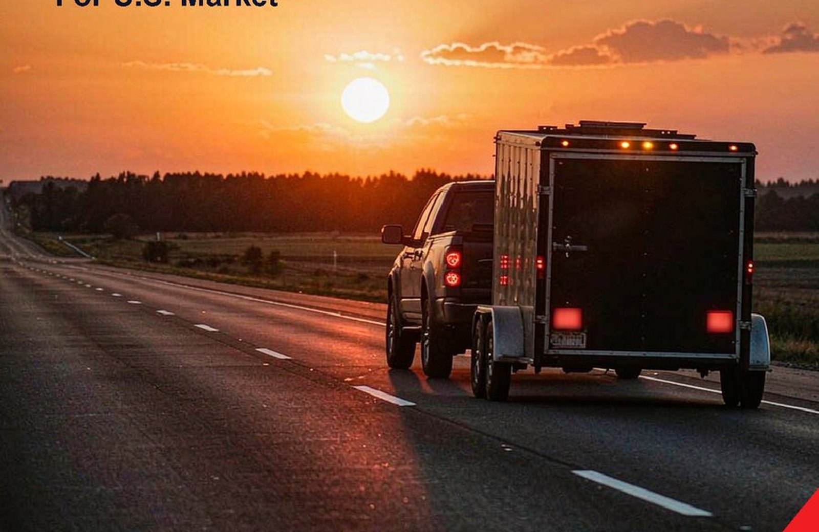 A pickup towing an enclosed trailer at sunset on an open highway, with the trailer's LED tail lights illuminated.